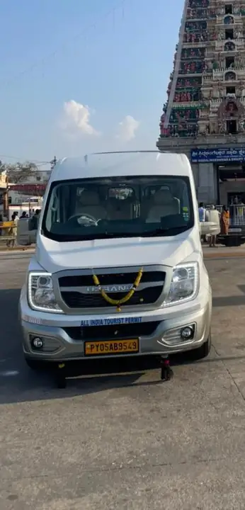 Silver Urbania van garlanded and parked in front of a temple tower